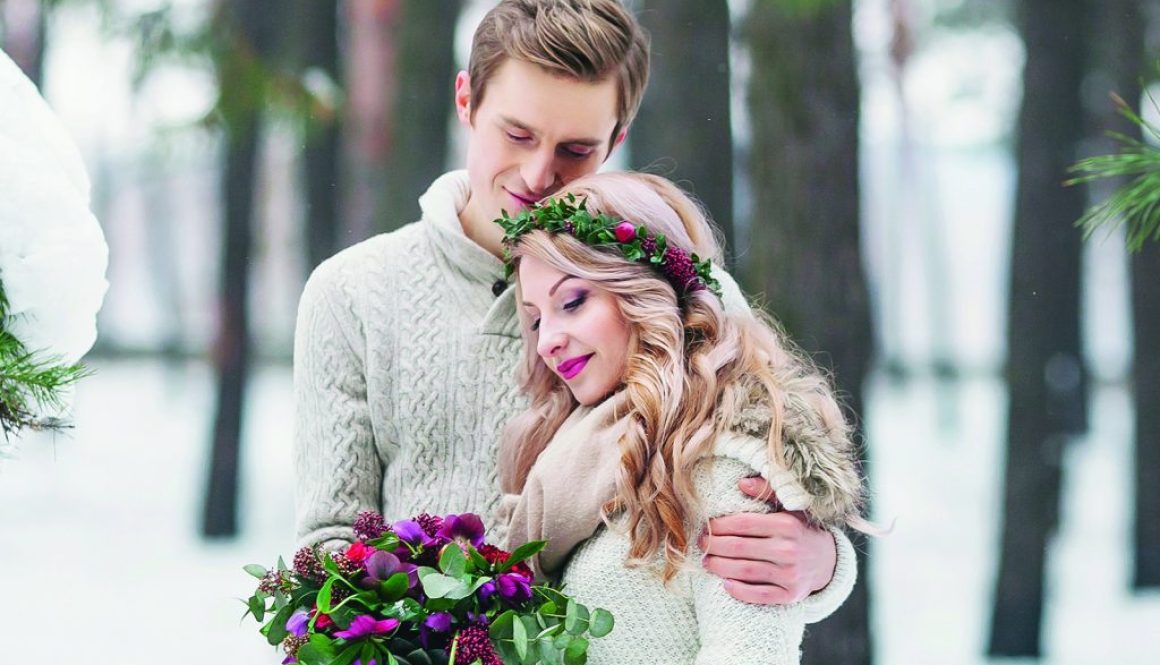 Bride with wreath and bouquet, groom in beige knitted pullover are walking in snowy forest. Winter wedding. Artwork.