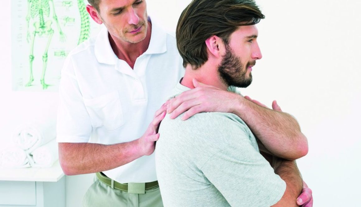 Male physiotherapist examining a young man in the medical office