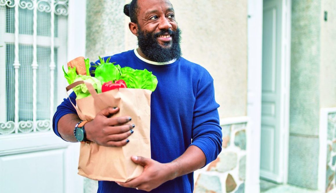 African american man with beard holding paper bag of groceries from supermarket