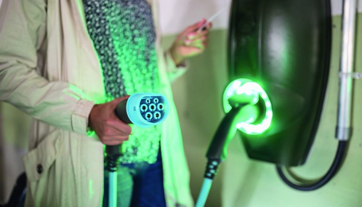 Young woman charging an electric vehicle in an underground garag