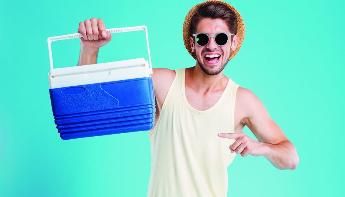 Happy young man holding and pointing on cooler bag