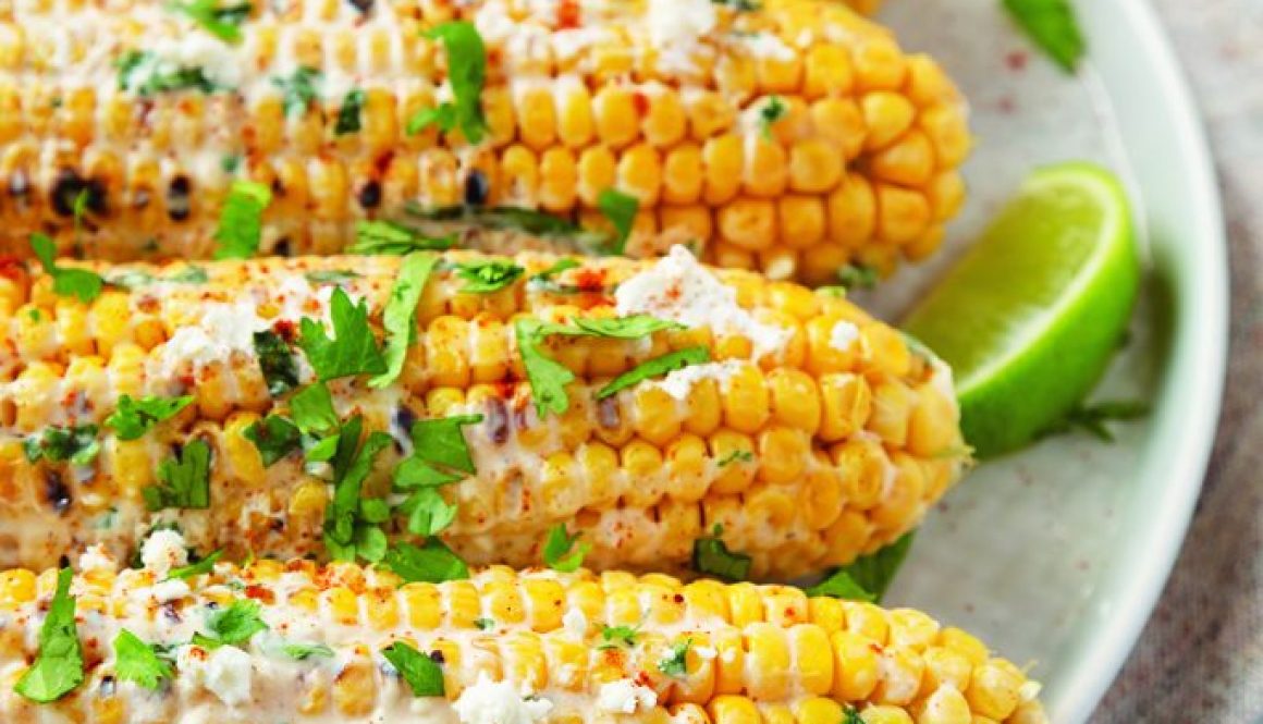 Homemade Elote Mexican Street Corn on a plate, side view.