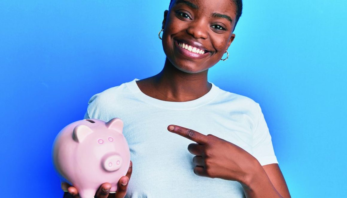 Young african american woman holding piggy bank smiling happy pointing with hand and finger