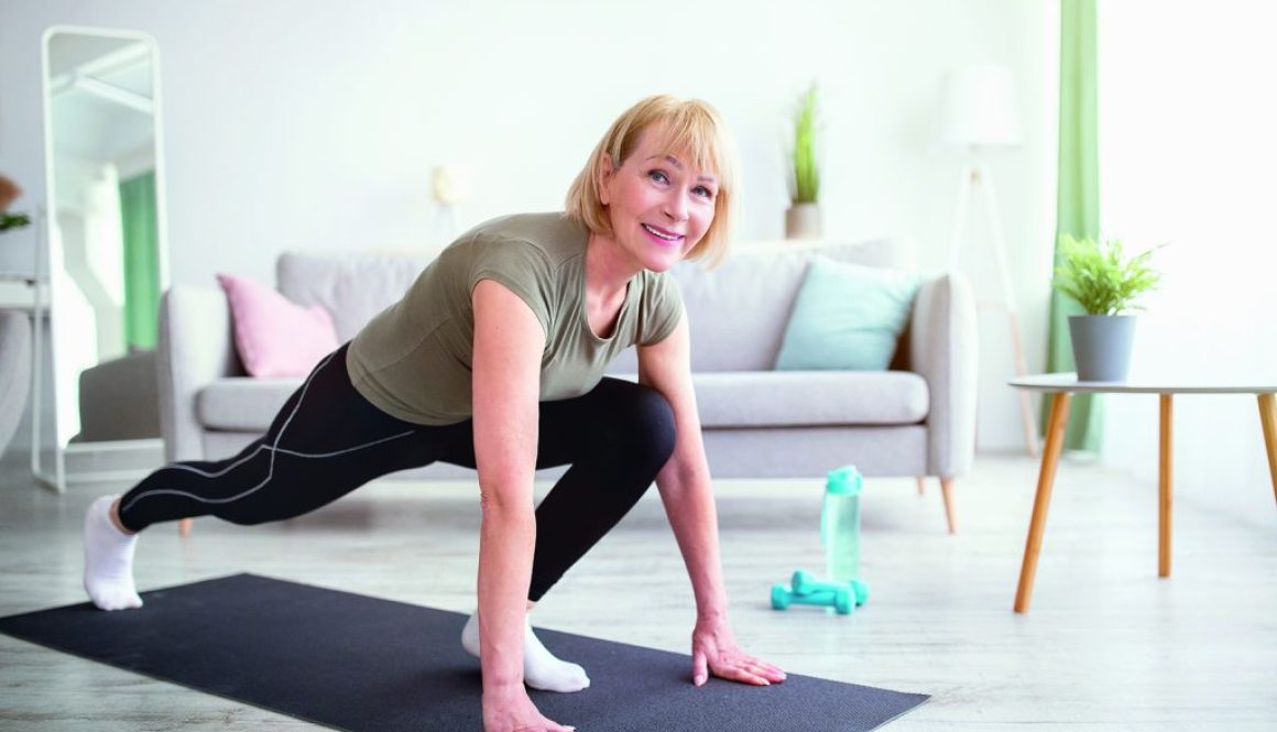Positive athletic senior woman doing runner's lunge yoga pose on home workout, copy space