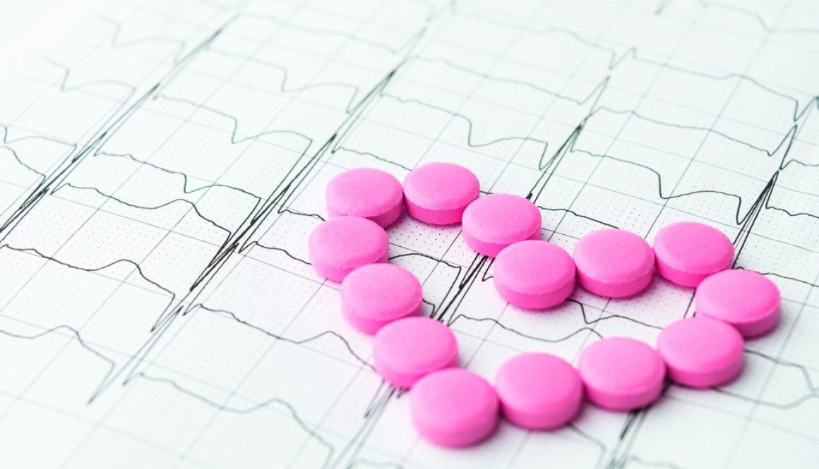 Heart of pink pills on paper cardiogram