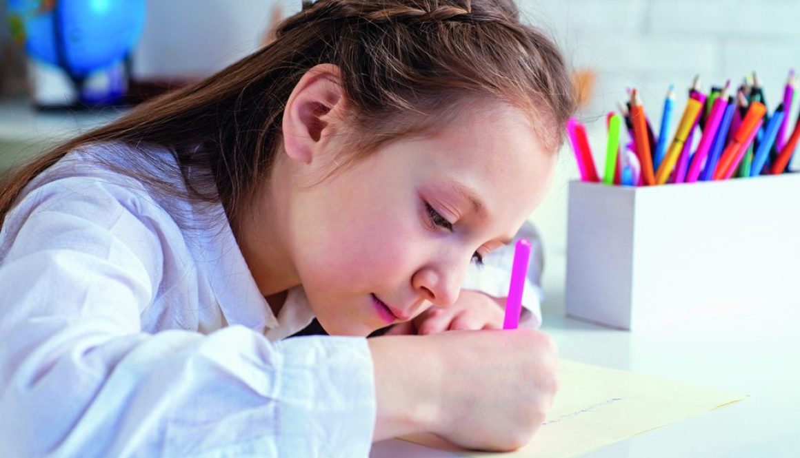 Happy cheerful child girl drawing. Creativity concept. Cute child drawing using felt-tip pen while sitting at table.