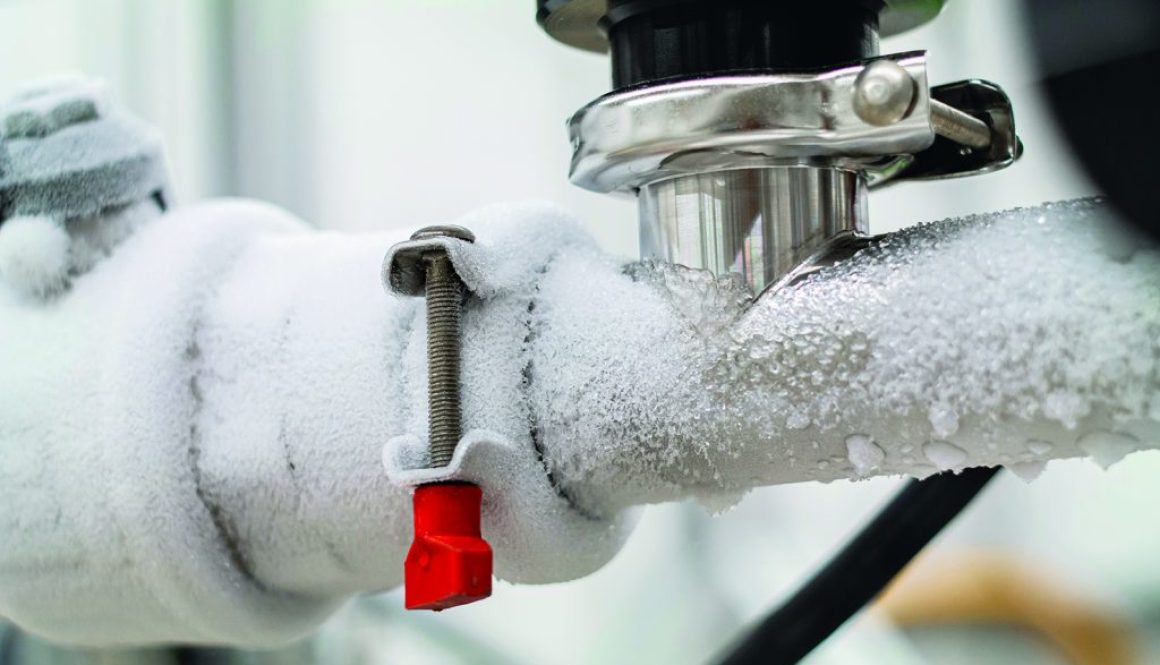 Frozen liquid nitrogen carrying pipes with a valve and black plastic lever close up in a science laboratory