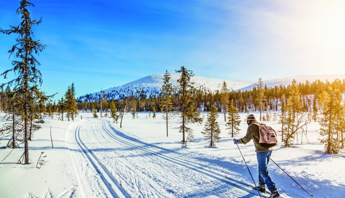 Tourist cross-country skiing in Scandinavia at sunset