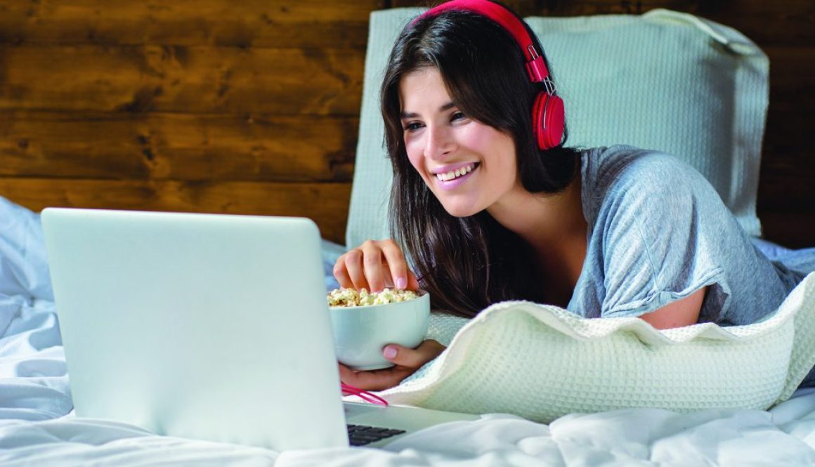 Woman eating popcorn and watching movies in bed