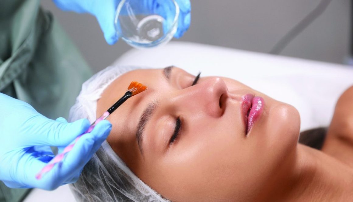 Cosmetologist applying chemical peel product on client's face in