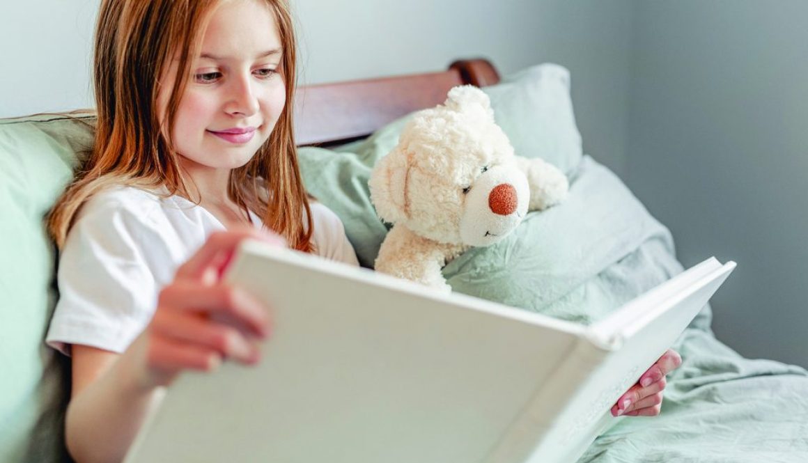 Child girl with teddy bear toy in the bed
